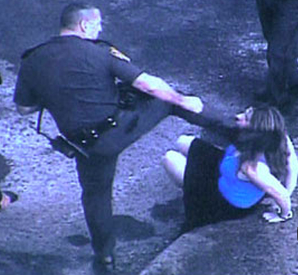 Rhode Island Police Officer Edward Krawetz practicing a roundhouse kick on a seated handcuffed woman